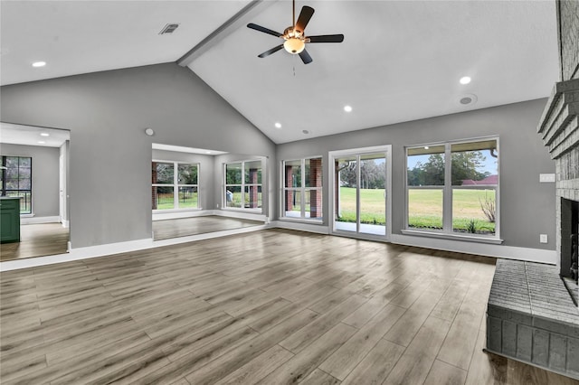 unfurnished living room with beamed ceiling, high vaulted ceiling, a brick fireplace, and ceiling fan