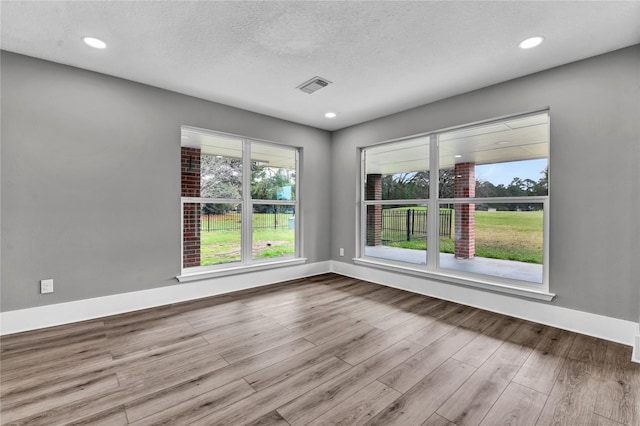 spare room featuring a textured ceiling and light wood-type flooring