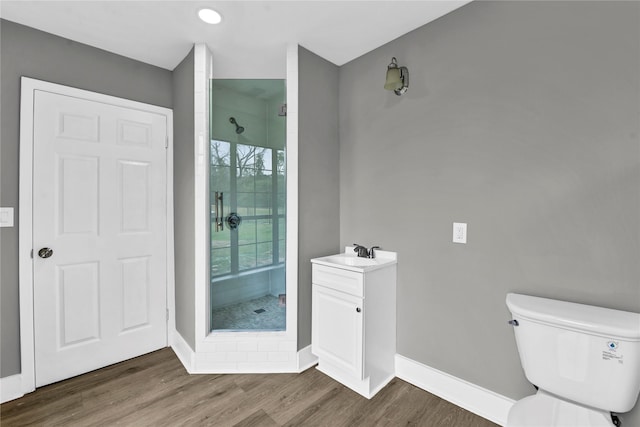 bathroom with toilet, vanity, wood-type flooring, and tiled shower