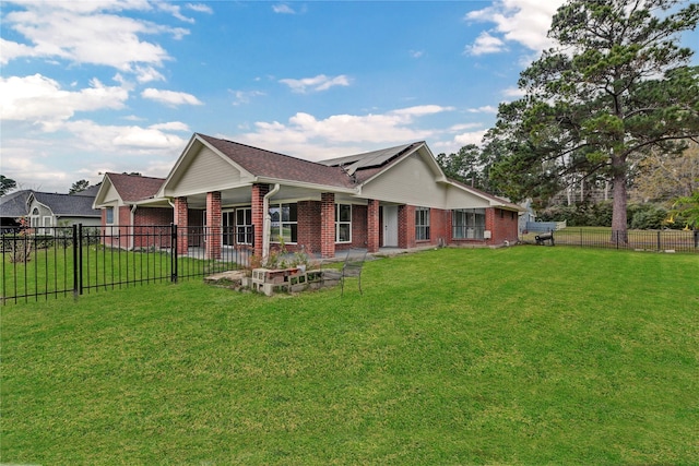 rear view of property with solar panels and a lawn