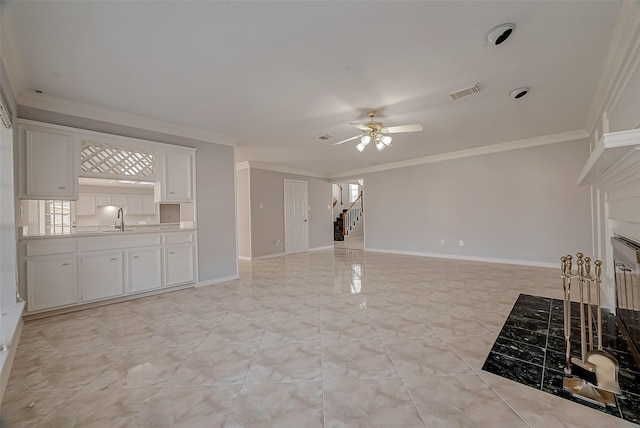 unfurnished living room featuring ceiling fan, sink, crown molding, and a wealth of natural light