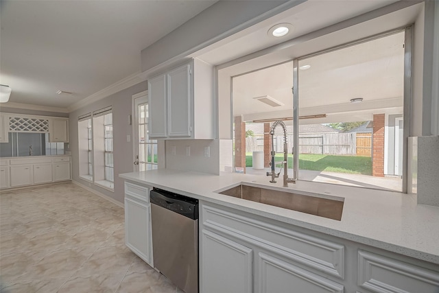 kitchen with sink, stainless steel dishwasher, ornamental molding, tasteful backsplash, and white cabinetry