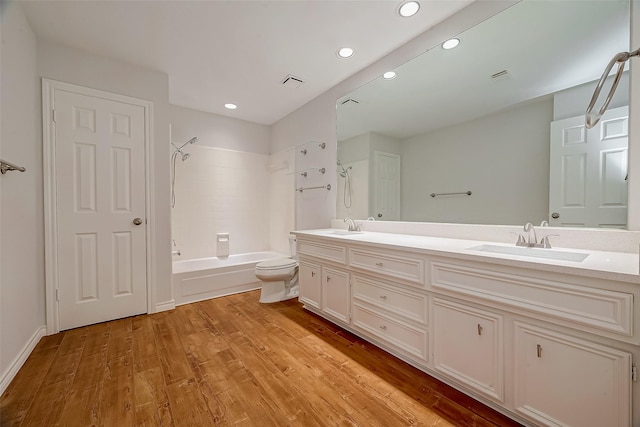 full bathroom with washtub / shower combination, wood-type flooring, vanity, and toilet