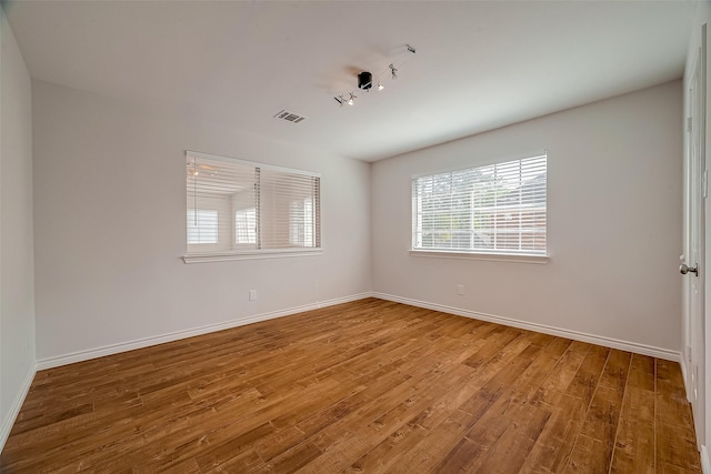 unfurnished room featuring hardwood / wood-style floors and rail lighting