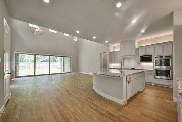 16146 Rustling Woods Rd, Conroe, TX 77302 - kitchen with built in microwave, double oven, backsplash, light wood-style floors, and recessed lighting