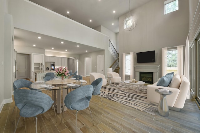 16146 Rustling Woods Rd, Conroe, TX 77302 - dining room featuring wood finished floors, recessed lighting, a high ceiling, a glass covered fireplace, and stairs