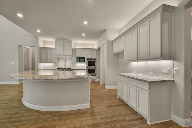 16146 Rustling Woods Rd, Conroe, TX 77302 - kitchen featuring double oven, decorative backsplash, light wood-style floors, built in microwave, and recessed lighting