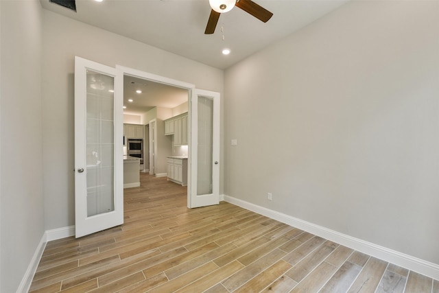 16146 Rustling Woods Rd, Conroe, TX 77302 - empty room with a ceiling fan, light wood-style floors, french doors, and recessed lighting
