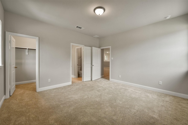 16146 Rustling Woods Rd, Conroe, TX 77302 - unfurnished bedroom with light colored carpet, a spacious closet, and ensuite bathroom