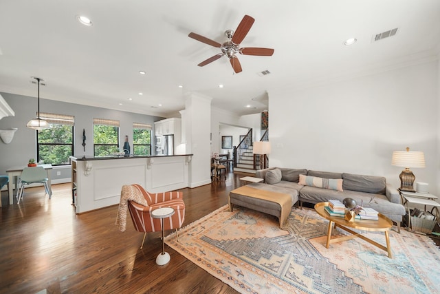 living room with ornamental molding, ceiling fan, and dark wood-type flooring