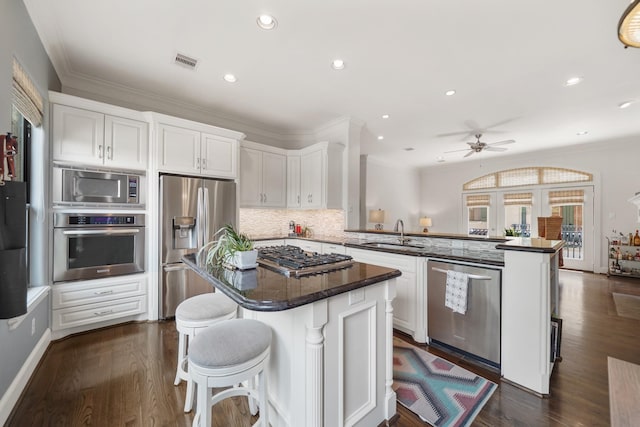 kitchen featuring kitchen peninsula, a center island, stainless steel appliances, and white cabinetry