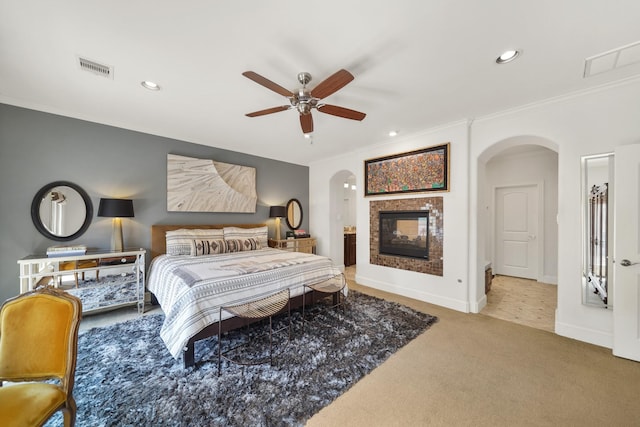 carpeted bedroom featuring ceiling fan, a multi sided fireplace, and crown molding