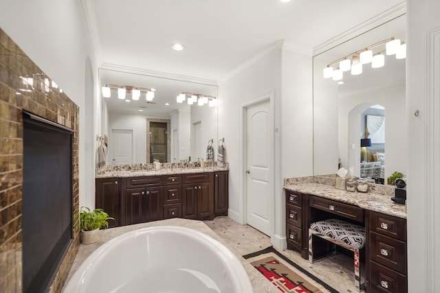 bathroom featuring tiled bath, crown molding, and vanity