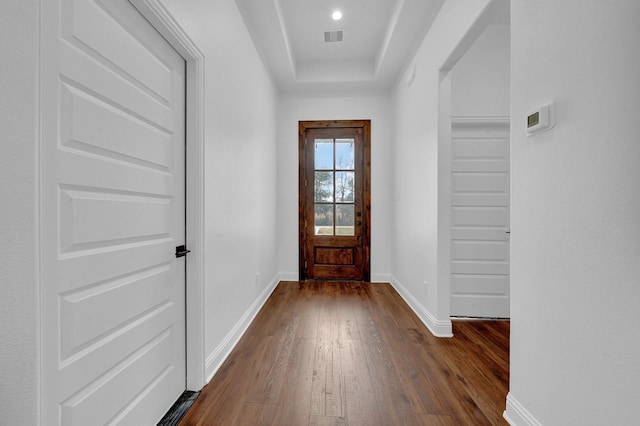 doorway featuring dark hardwood / wood-style flooring and a tray ceiling