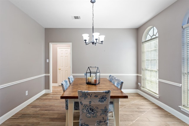 dining area featuring light wood-type flooring and a notable chandelier