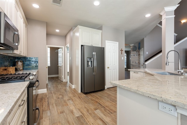 kitchen with sink, tasteful backsplash, light stone counters, white cabinetry, and stainless steel appliances