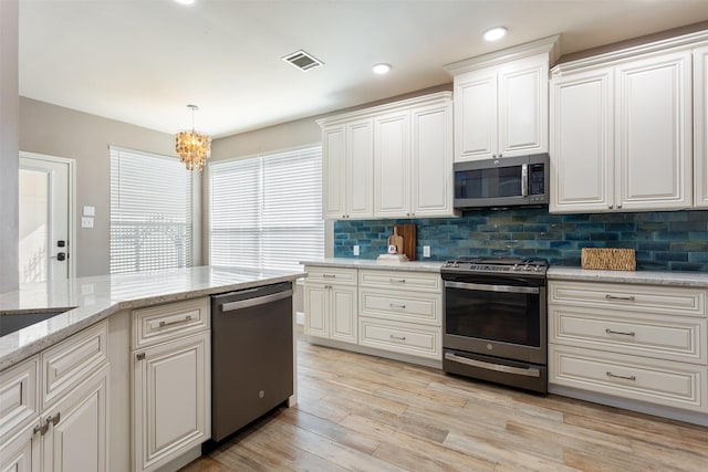 kitchen with white cabinetry, light stone counters, decorative light fixtures, decorative backsplash, and appliances with stainless steel finishes