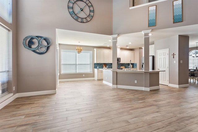 kitchen with a center island with sink, pendant lighting, light wood-type flooring, and appliances with stainless steel finishes