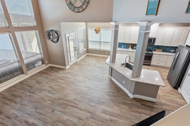 kitchen with light stone countertops, white cabinetry, stainless steel appliances, and tasteful backsplash