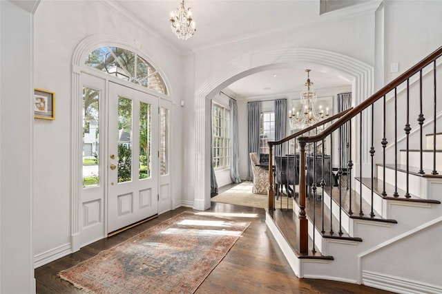 foyer entrance with a wealth of natural light, crown molding, dark hardwood / wood-style flooring, and a notable chandelier