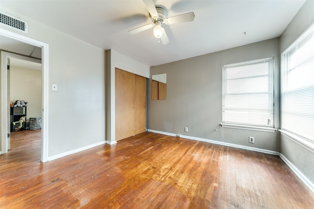 unfurnished bedroom with ceiling fan, wood-type flooring, and multiple windows