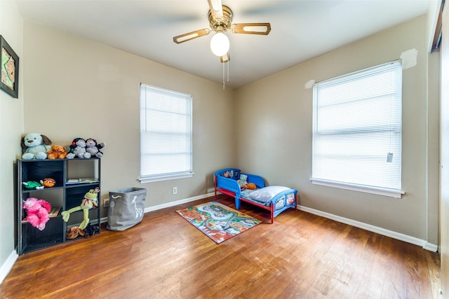 bedroom with ceiling fan, wood-type flooring, and multiple windows