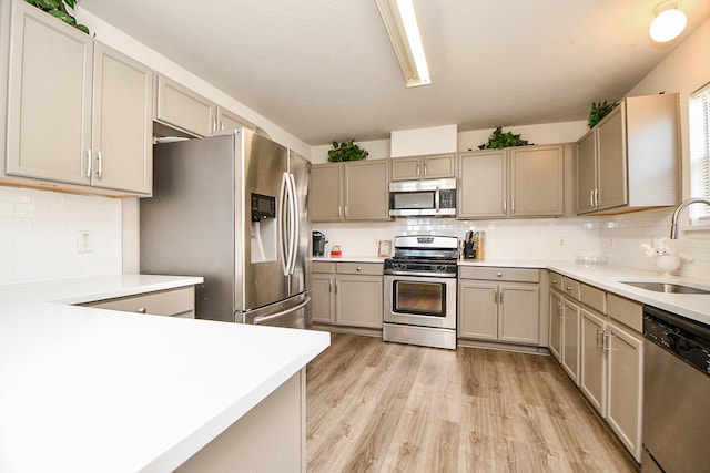 kitchen featuring a sink, light wood-style flooring, stainless steel appliances, and light countertops