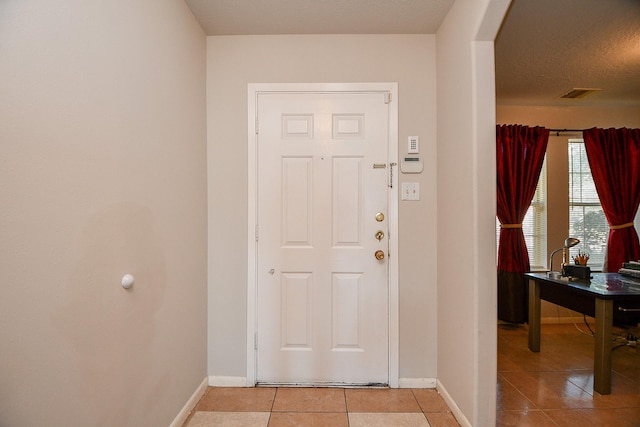 foyer entrance featuring a textured ceiling and light tile patterned floors