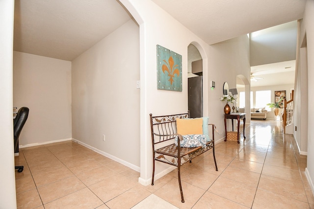 hall featuring baseboards and light tile patterned floors