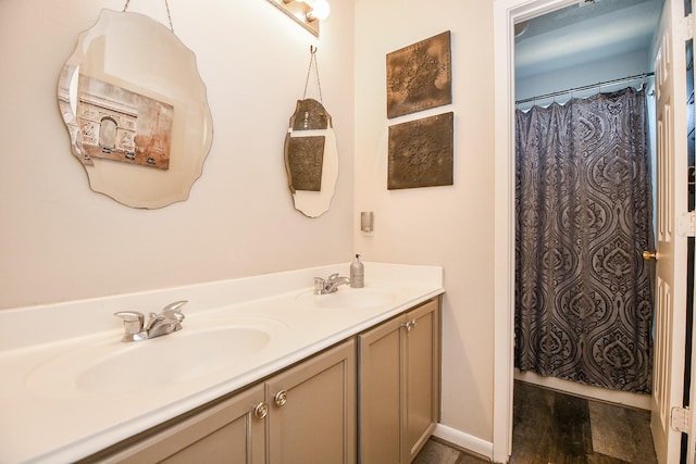 bathroom featuring double vanity, baseboards, a sink, and wood finished floors