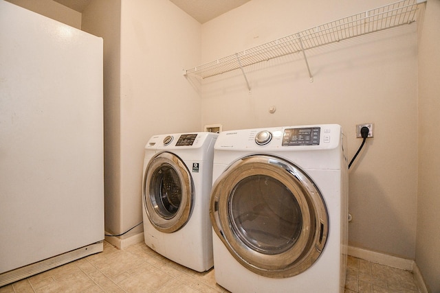 laundry area with laundry area, independent washer and dryer, and baseboards