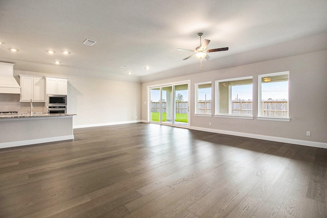 unfurnished living room featuring dark hardwood / wood-style floors, ceiling fan, and a healthy amount of sunlight