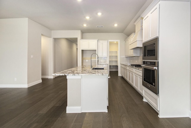 kitchen with light stone countertops, tasteful backsplash, stainless steel appliances, a kitchen island with sink, and sink