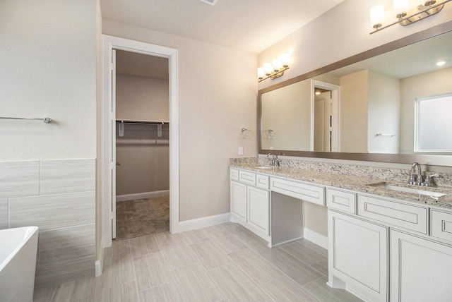 bathroom with vanity, tile walls, and a tub