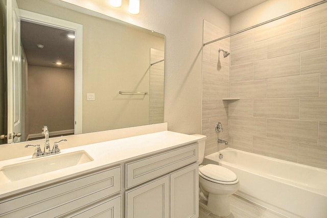 full bathroom featuring vanity, tiled shower / bath combo, and toilet