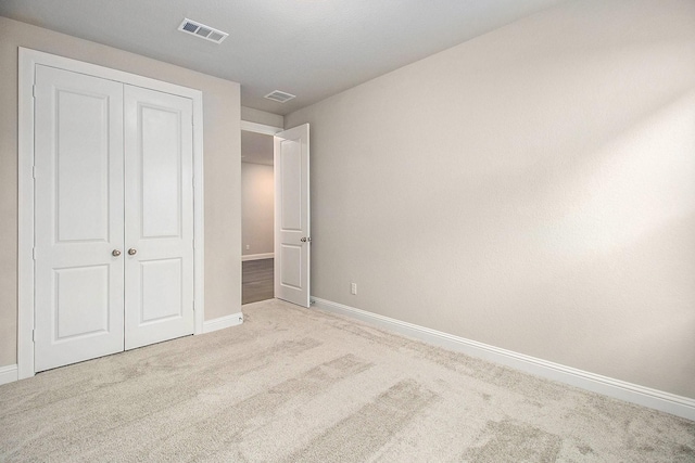 unfurnished bedroom featuring light carpet and a closet