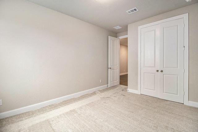 unfurnished bedroom featuring light carpet and a closet