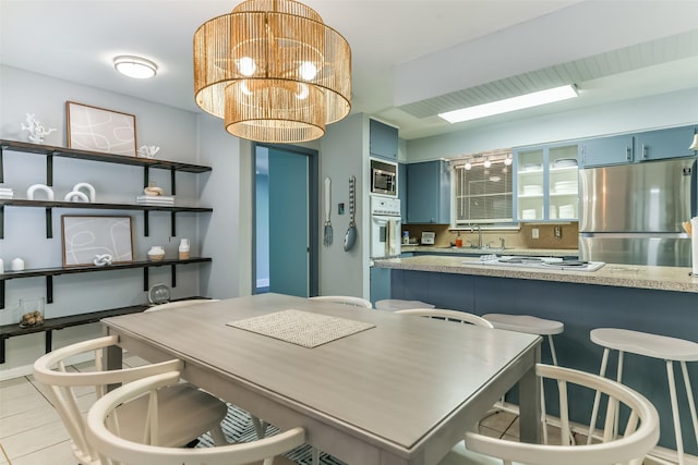 dining space with a notable chandelier, light tile patterned flooring, and sink