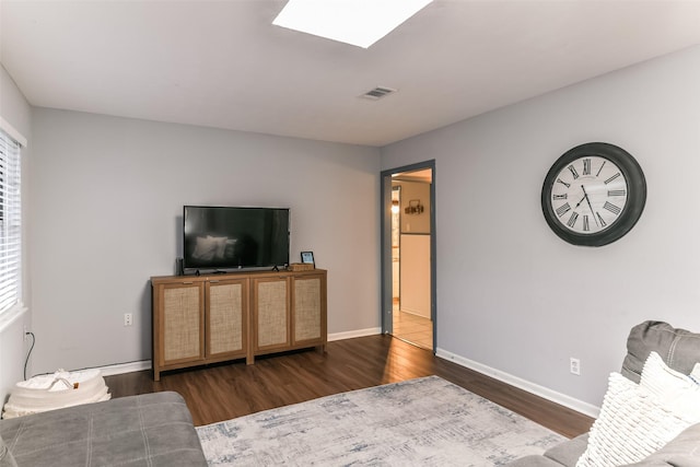 living room featuring a skylight, a wealth of natural light, and dark wood-type flooring