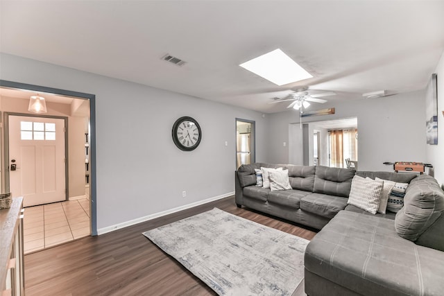 living room with dark hardwood / wood-style flooring, a skylight, and ceiling fan