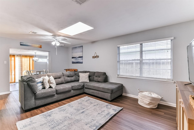 living room with a skylight, ceiling fan, and dark wood-type flooring