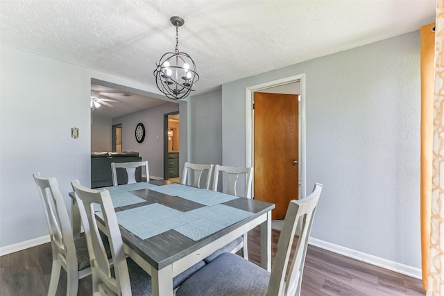 dining room with ceiling fan with notable chandelier, a textured ceiling, and dark wood-type flooring