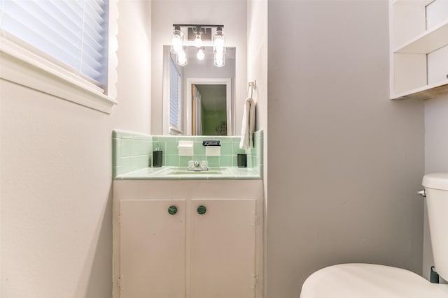 bathroom featuring vanity, toilet, and backsplash