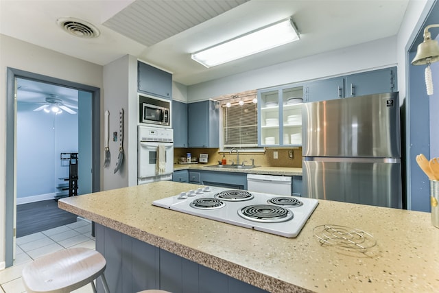 kitchen with sink, a kitchen breakfast bar, blue cabinets, light tile patterned floors, and appliances with stainless steel finishes