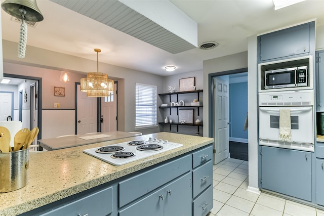 kitchen featuring white appliances, blue cabinets, decorative light fixtures, light tile patterned floors, and a notable chandelier