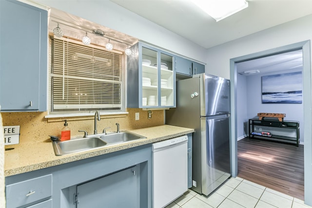 kitchen with dishwasher, sink, decorative backsplash, light tile patterned floors, and stainless steel refrigerator