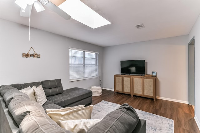 living room featuring a skylight, ceiling fan, and dark wood-type flooring