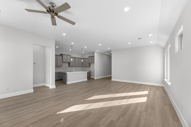 unfurnished living room with ceiling fan, sink, and light hardwood / wood-style floors