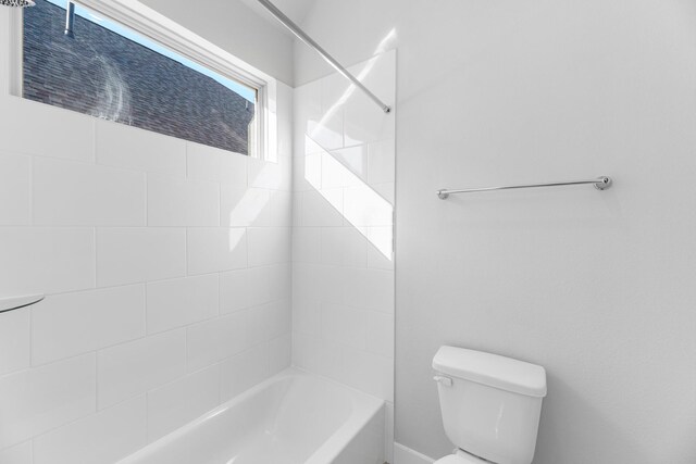 bathroom featuring tiled shower / bath combo and toilet