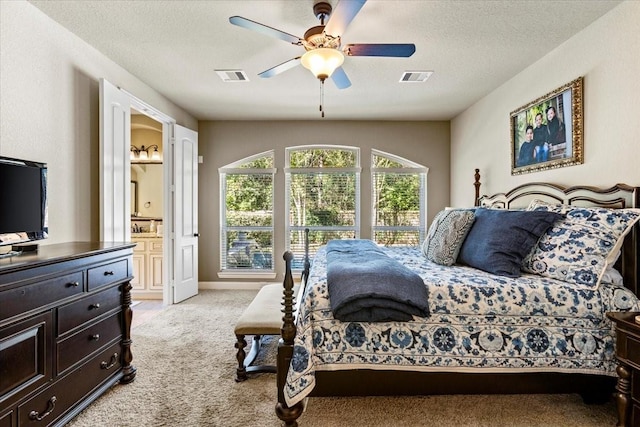 bedroom with light carpet, a textured ceiling, ensuite bath, and ceiling fan